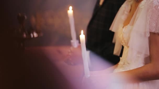 Närbild fotografering av brinnande ljus hålls i kyrkan. Bröllopspar brudgummen i kostym och bruden i vit klänning. Kristna vackra kyrka bröllop, Ukraina. Troende par i kärlek — Stockvideo