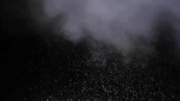Para ze śniegiem latającym w próżni i wymieszanym na czarnym tle. Dym papierosowy ze śniegiem w odosobnionym miejscu. Burza śnieżna z mgłą wznosi się w powietrzu na tle całkowitej ciemności.. — Wideo stockowe