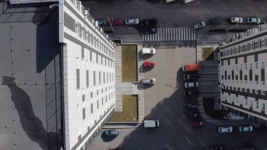 Kharkov, Ukrayna 'daki beyaz çok katlı binaların girişindeki bölgenin üst görüntüsünden uzaklaşıyoruz. Kışın güneşli bir havada, yüksek katlı bir binanın yakınında araba park yeri olan özel bir bahçe..
