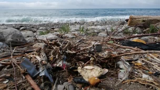 Pile d'ordures gisant sur le bord de la mer sur fond de marées de vagues, vue rapprochée au ralenti. La tragédie écologique du colmatage des terres. Le problème mondial de l'humanité est l'élimination des ordures . — Video