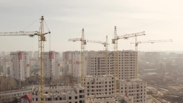 Tiro em altura de vários guindastes de construção amarelos e construção de novos edifícios para habitação e escritório no centro de Kharkov, Ucrânia. Construtores estão fazendo um novo edifício alto, vista superior . — Vídeo de Stock