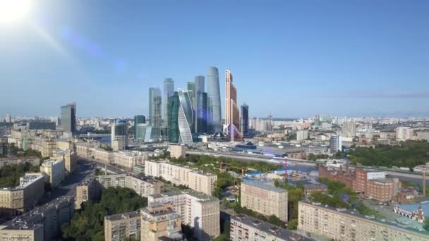 Vista aérea de drone arranha-céus da cidade de Moscou através de raios de sol. Centro de negócios de Moscou-cidade. Torres internacionais e casas da capital da Rússia com chama solar. Tráfego de acima vista de olhos de pássaros — Vídeo de Stock
