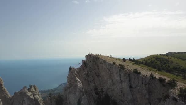 Voo sobre a famosa montanha Ai-Petri e uma ponte suspensa extrema para levantar até o topo na Crimeia, Yalta, Ucrânia. Os turistas em uma caminhada vão ao pico da montanha. Passando sobre o abismo . — Vídeo de Stock