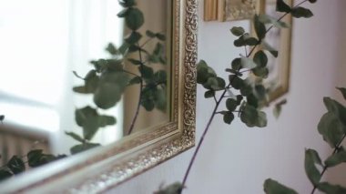 Yapraklı bir buket çiçeğin kökü aynaya yansıyarak çerçevenin arka planında erkeğin resmedildiği portreyi yansıtır. Aynanın yanındaki kaidede duran bitkinin yakın görüntüsü.