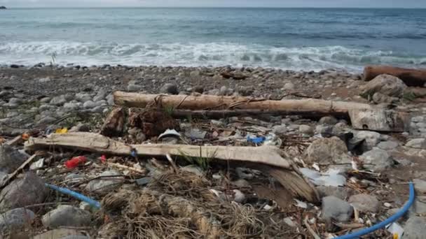 Verstopte kust te midden van vloedgolven. Ecologische tragedie van water- en landvervuiling door afval. Milieuvervuiling door mensen. Lang rottend afval aan land. Kleine stortplaats bij de oceaan, dichtbij uitzicht. — Stockvideo