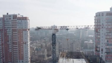 Bir inşaat sahasında vinç yardımıyla modern bir gökdelen inşaatı, üst manzara. İşçiler çatıda duruyor ve evin yeni bir zeminini inşa ediyorlar, Kharkov, Ukrayna.
