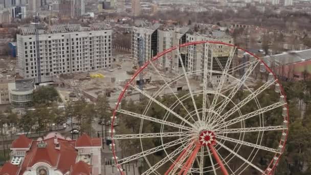 Närmar flygfoto av den berömda pariserhjulet i Kharkov i Gorkij Park och byggarbetsplats med kranar bakom park där nya höghus byggs. Storskalig stadsutveckling — Stockvideo