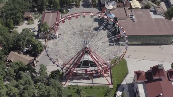 Tiro aéreo da altura de trabalhar a roda de Ferris no verão abaixo do sol brilhante quente. Famosa atração interessante em Gorky Park, na cidade de Kharkov, Ucrânia. Entretenimento para adultos e crianças . — Vídeo de Stock