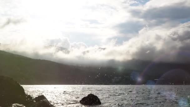Šplouchání a kapky z rozbité mořské vlny na kamenech na pozadí krásných mraků na obloze a slunečného jarního počasí na Krymu na Ukrajině. Oceánské vlny šplouchají na pobřežní kameny. Nádherná příroda. — Stock video