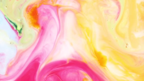 Gros plan sur le mélange de belle peinture rose et jaune dans du lait blanc. Dans un liquide brillant multicolore, de la peinture rose coulée pour designer. Taches et textures abstraites mélangées et dissoutes en fond blanc . — Video