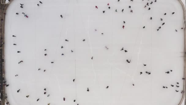 Bovenaanzicht van een winterijsbaan en mensen die in slow motion schaatsen. Winterijsbaan in de frisse lucht. Nuttige en interessante sport voor de gezondheid. Nieuwjaar en kerstdagen in Kharkiv, Oekraïne 2020. — Stockvideo