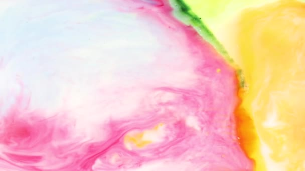 Beau mélange de jaune rose et un peu de peinture verte sur fond blanc. Des couleurs multicolores lumineuses abstraites se dissolvent dans le lait pour le concepteur. Liquide blanc mélangé avec vue rapprochée multicolore . — Video