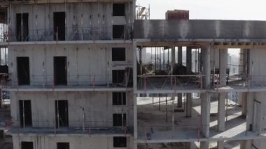 Kış mevsiminde kentte yeni bir modern çok katlı bina inşa etme süreci. Mavi inşaat vinci ve bina çatısının arka plandaki alçak evlerin görüntüsü..