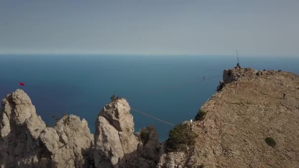 Oszałamiający krajobraz Morza Czarnego i gór Ai-Petri pod słońcem - najwyższa góra na Krymie w sezonie wiosennym, Jałta, Ukraina. Ludzie wspinają się na most. Sporty ekstremalne. — Wideo stockowe