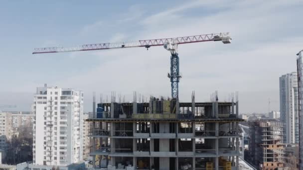 Letecký záběr na boku stavebního jeřábu nové vysoké budovy pod kanceláří během dne na pozadí moderních výškových budov, Charkov, Ukrajina. Výstavba domu. — Stock video