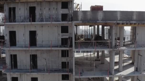 Le processus de construction d'un nouveau bâtiment moderne de plusieurs étages dans la ville pendant la saison hivernale. Vue aérienne de la grue de construction bleue et du toit de la construction sur fond de maisons basses résidentielles . — Video