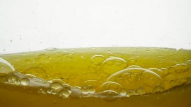 Lezzetli mısır ve soya yağı yüzeyinde büyük ve küçük hava kabarcıkları, yakın çekim. Güzel bir altın sıvı bir daire içinde suyla hafifçe karışır ve bir hava damlası yapısı belirir..