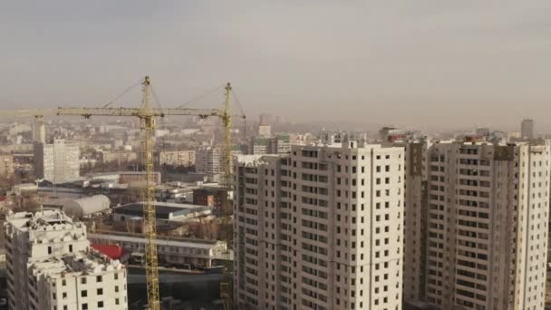 Budowa nowych nowoczesnych wieżowców biurowych i mieszkaniowych, suwnic wieżowcowych w kolorze żółtym. Panorama miasta przemysłowego. Budowa nowych budynków przez pracowników. — Wideo stockowe