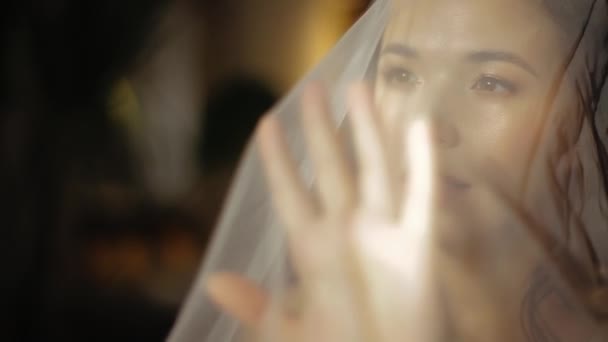 Morning of happy young european bride in wedding veil, slowly pulling the veil forward, close-up view. Bright sun rays falling on the face of pretty girl with make-up and in white veil. Morning woman. — Stock Video