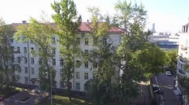 Rusya 'nın başkenti Moskova' da, güneşli sonbahar havasında ağaçlarla çevrili konut binasına ya da üniversiteye benzeyen beyaz binanın en üst manzarası. Bina, aşağıdaki otoparklı bir pansiyondur..