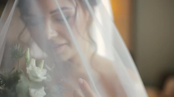 Šťastná krásná evropská nevěsta v elegantních svatebních šatech a závoji drží kytici barevných květin a po ránu se směje štěstím v hotelovém pokoji. Žena se připravuje na svatbu.. — Stock video