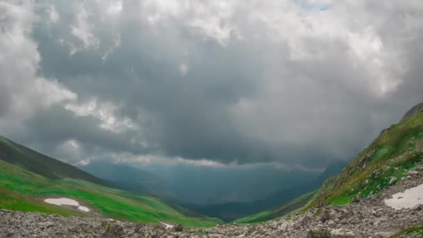 巨大な移動積雲を背景に草や石で覆われたアディヤ山脈の見事な緑の谷の美しいパノラマの景色。春の自然の時間経過 — ストック動画