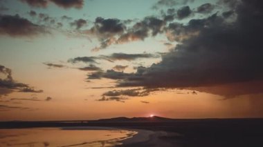 İlkbaharda yoğun hareket eden bulutların altında gün batımı ve turuncu gökyüzü ile körfezin göz kamaştırıcı panoramik üst görüntüsü. Karadeniz 'in ve Kırım' daki dağların manzarasının güzel zamanı