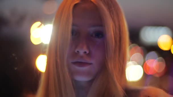 Esti fotózás bájos fiatal európai szőke lány áll az utcán a város központjában világítás alatt, és elegánsan pózol a kamera hátterében fényes homályos fények, közelkép. — Stock videók