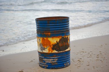 Çevre kirliliği. Beach kirliliği. Bir eski, aşınmış varil sahilde yaptı. Mavi boya ve pas. Kum ve deniz arka planda.