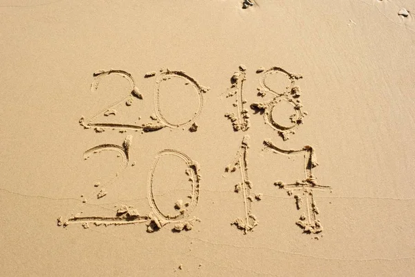 Yeni yıl geliyor! 2018 ve diğer altında kum birinde yazılı 2017.