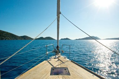 Front deck of a sailing yacht with beautiful sea and islands in the background. clipart