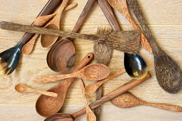 Wooden spoons and spatulas laid out chaotically on wooden background.