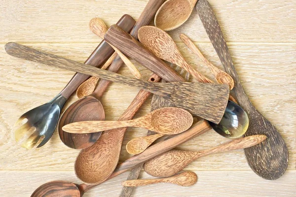 Wooden spoons and spatulas laid out chaotically on wooden background.