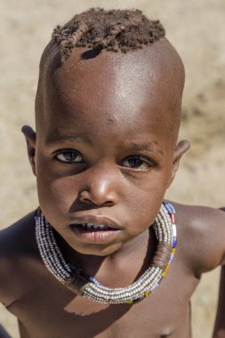 Opuwa, Bölge: Kunene, Namibia, 17 Ekim 2017: geleneksel iki örgülü hairplates ileri genişletilmiş gösterilen genç Himba kız