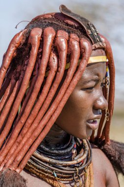 Opuwa, Kunene bölge, Namibya, 17 Ekim 2017: Himba kadın geleneksel bir kolye taşıyan ve dokulu otjize saç levha gösterilen otjize yapıştır ile kaplı