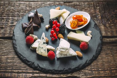 Peynir kurulu ile farklı tip-in peynir, çikolata, ahududu, böğürtlen, frenk üzümü, badem, üzüm ve karamel ahşap eski tablo ile