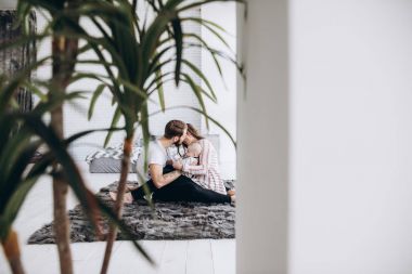 Annem ve babam pencerenin yakınındaki halının üstünde oturan sevimli küçük kızları ile birlikte vakit geçirmek