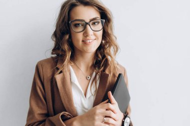 Elleri ayakları beyaz bir duvar yakınındaki bir dizüstü bilgisayar ile büyüleyici bir gülümseme ile güzel bir kadın portresi. Bir metin için boş alan