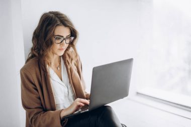 Genç güzel iş kadın gözlük üstünde laptop ofisinde çalışıyor.