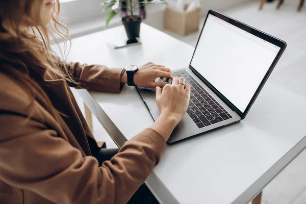 Female hands typing on the laptop. White blank laptop screen with space for text