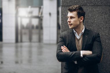 Gri bir arka plan açık havada şık bir ceket bir yakışıklı gülümseyen adam portresi