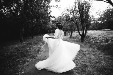 Çok güzel bir gelinlik gelin ona düğün gününde Bahçe etrafında yürüyor. Siyah ve beyaz fotoğraf