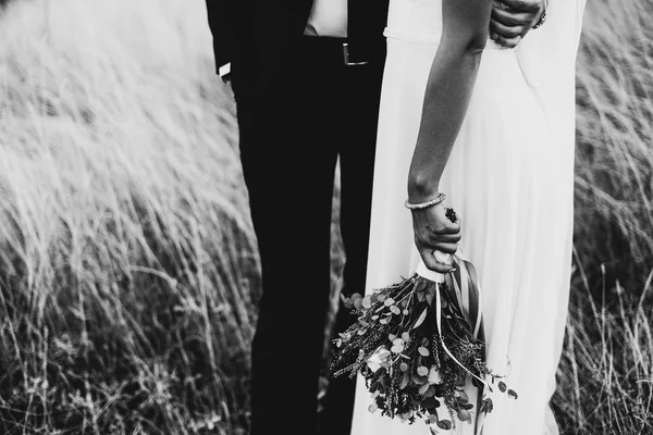 在户外的一对新婚夫妇的黑白照片 新郎拥抱新娘新娘手里捧着结婚花束 — 图库照片