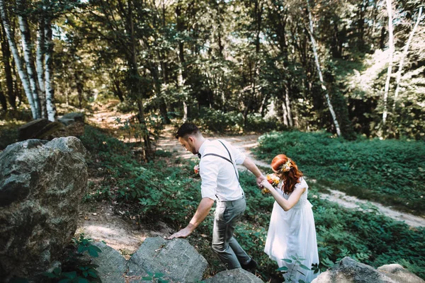 Newlyweds walking in the woods in wedding dresses