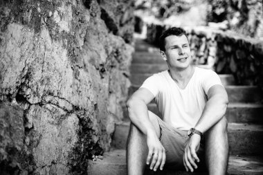 Merdivenlerde bir yakışıklı karizmatik adam portresi. Siyah ve beyaz fotoğraf