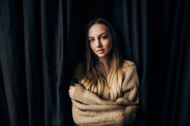 Uzun saç ve mavi gözlü siyah bir arka plan üzerinde duran bir şaşırtıcı gülümseyen kız görüntüsü. Kız Açık penceresinden ışık parlıyor