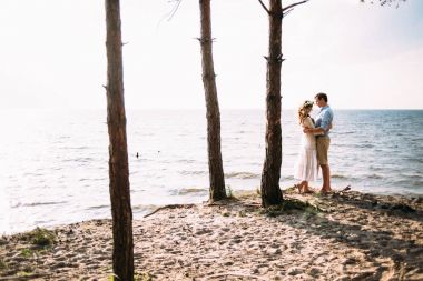 Sevgi dolu güzel bir çift günbatımında sahil üzerinde duran ve birbirine bakarak