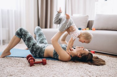 Evde spor var. Evde küçük tatlı kızıyla spor yapan genç ve çekici bir anne. 