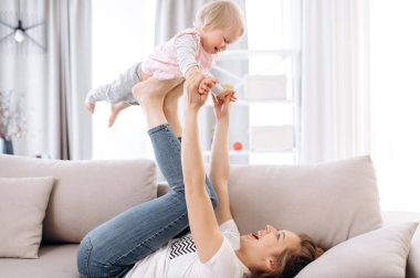 Hafta sonu evde. Mutlu anne ve küçük kızı evde birlikte eğleniyorlar kanepede uzanıp birlikte gülüyorlar. Mutlu annelik ve çocukluk