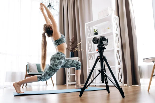 Fitness videosu dersi. Spor giyim sektöründeki atletik kız blogcu kameraya egzersiz ve spor antrenmanlarını nasıl yaptığını kaydediyor.